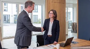 Händler und Kundin beim Handschlag im Büro